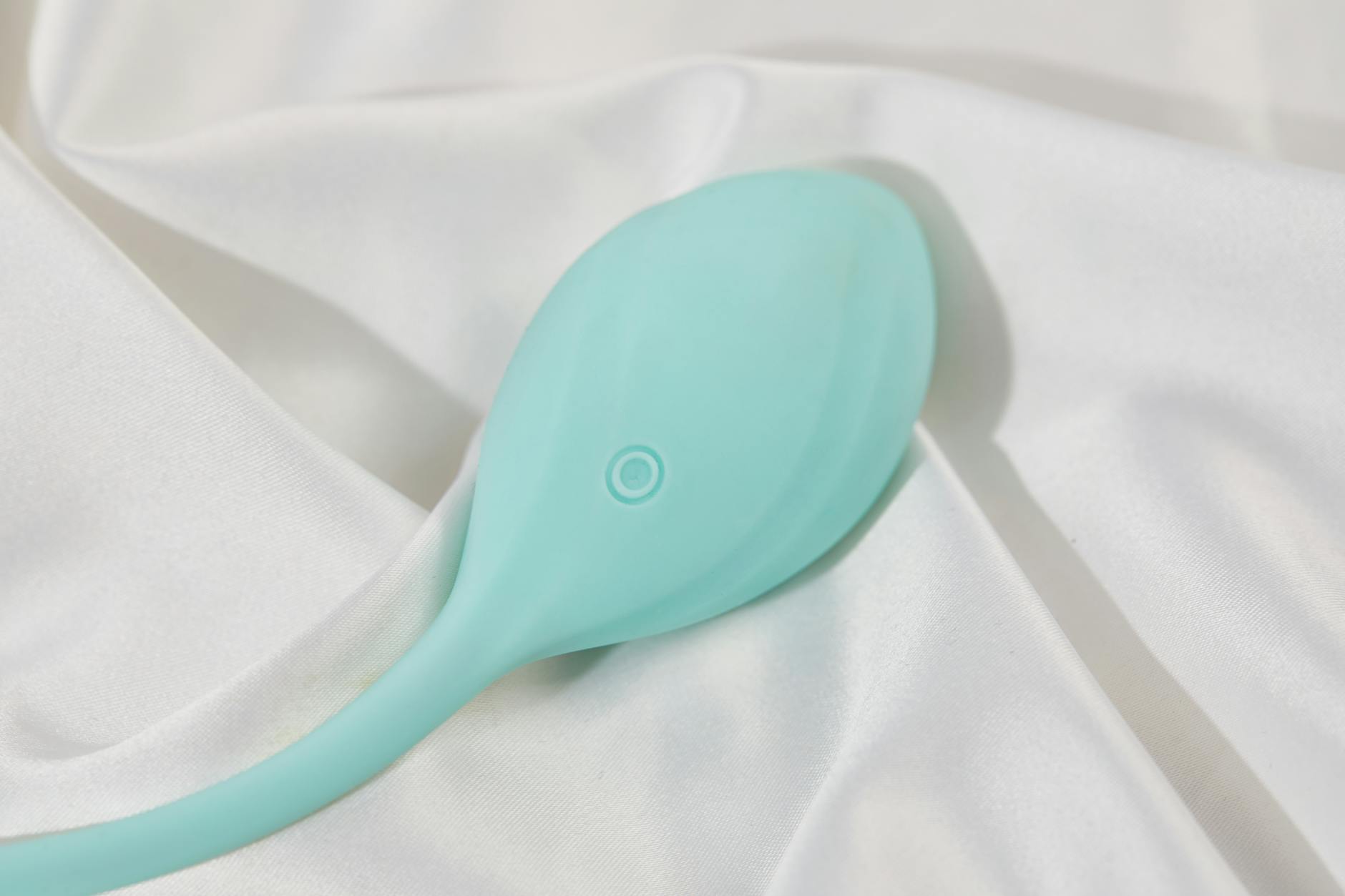 A teal lemon vibrator on smooth white silk, symbolizing gentle reconnection and embodied pleasure