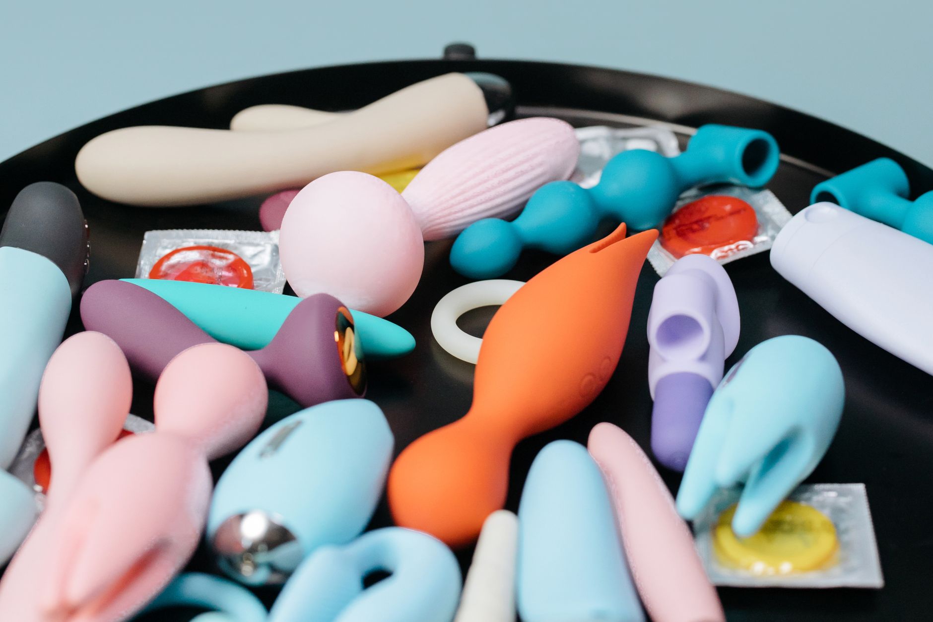 Three colorful clitoral vibrators arranged on white fabric