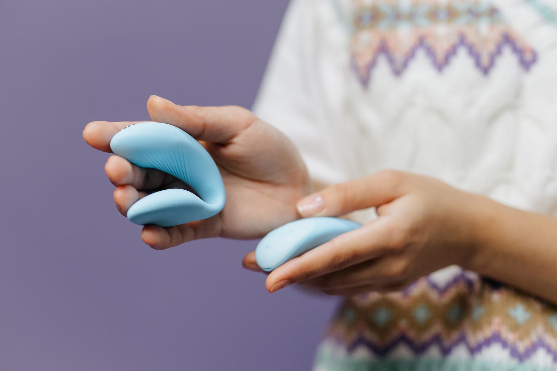 Close-up of hands holding a sleek blue clitoral vibrator, symbolizing intimate reconnection