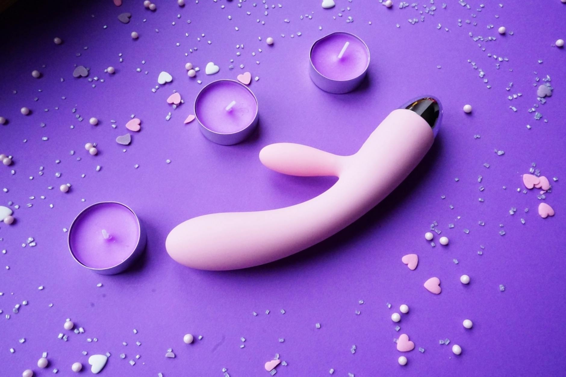 Three colorful clitoral vibrators arranged on white fabric
